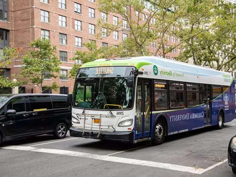 An electric shuttle bus on the street with Columbia University on it